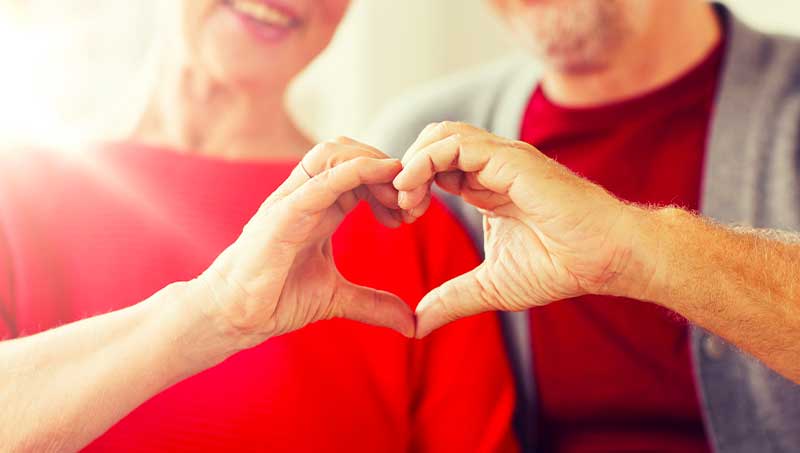 Mature couple holding hands in heart shape