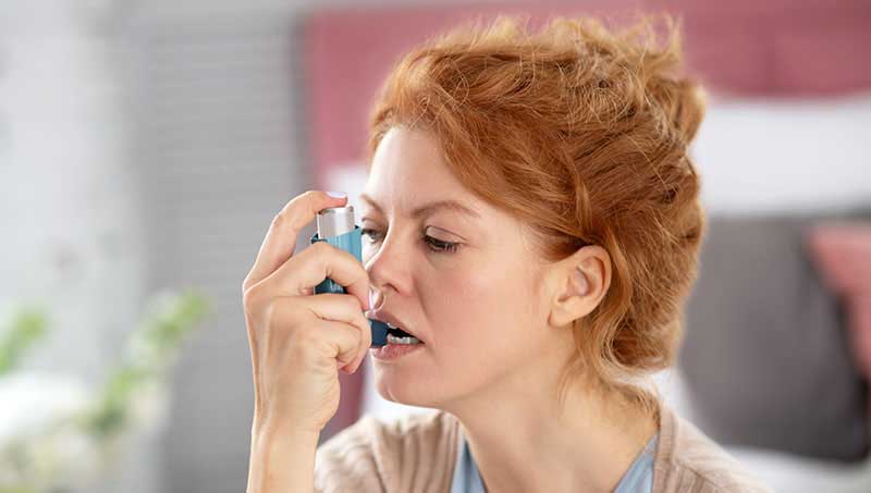 Woman using inhaler for asthma relief